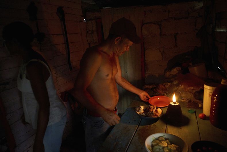 Edinector Vázquez se prepara para cenar en su casa iluminada por una lámpara de gas durante un apagón de luz en Minas, en la provincia de La Habana, Cuba, el lunes 26 de mayo de 2025. (AP Foto/Ramón Espinosa)