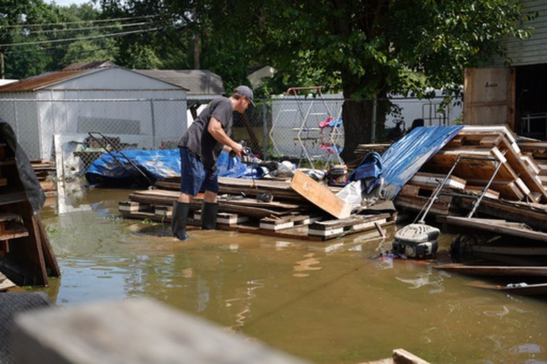 Frank Gounder saca equipo de su taller de carpintería afectado por las inundaciones en Indianápolis, domingo 16 de agosto de 2026. (Foto AP/Obed Lamy)