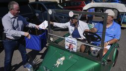 Una pareja deposita sus votos por correo en la urna sostenida por el supervisor electoral del condado Sumter, Bill Keen, en The Villages, Florida, el 14 de octubre de 2024. (Foto AP/Rebecca Blackwell)