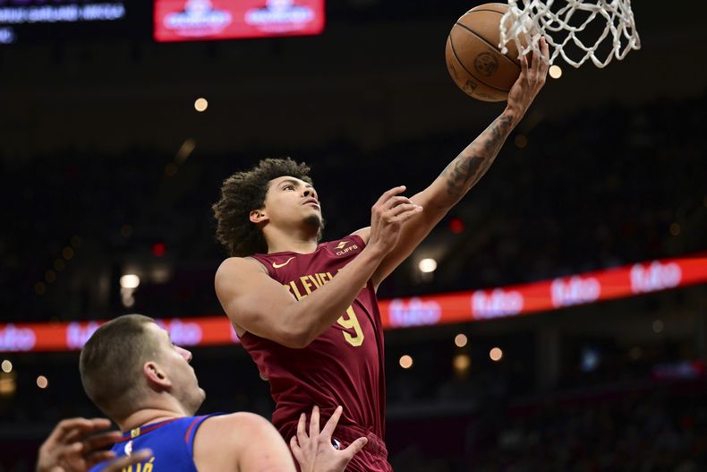Craig Porter, de los Cavaliers de Cleveland, se alista a encestar contra los Nuggets de Denver, ante la mirada de Nikola Jokic, en la segunda mitad del juego de baloncesto de la NBA, el domingo 19 de noviembre de 2023, en Cleveland. (AP Foto/David Dermer)