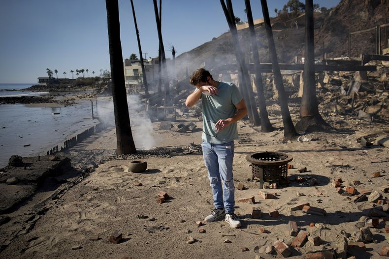 Luke Dexter reacciona mientras busca entre los restos de la casa de la playa de su padre, arrasada por el incendio Palisades, el 10 de enero de 2025, en Malibú, California. (AP Foto/John Locher)