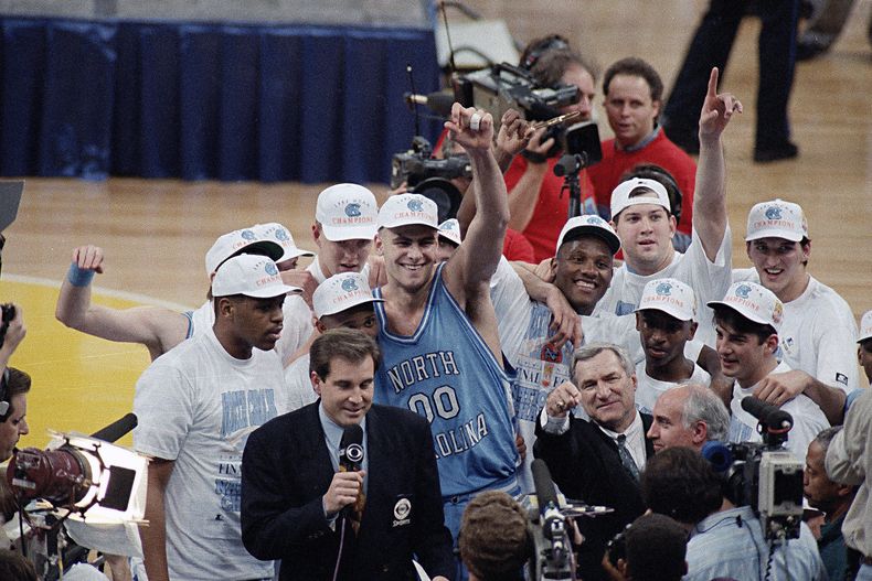 ARCHIVO - En esta foto de archivo del 5 de abril de 1993, Eric Montross (00), de North Carolina, alza el brazo mientras celebra la victoria contra Michigan en el juego de campeonato de la NCAA, en Nueva Orleans. Montross, quien brillara con North Carolina y en la NBA, falleció a los 52 años después de una batalla contra el cáncer. La Universidad emitió un comunicado el lunes 18 de diciembre de 2023, señalando que Montross murió el domingo rodeado de sus seres queridos en su casa en Chapel Hill. Fue diagnosticado con cáncer en marzo. (AP Foto/Bob Jordan, Archivo)