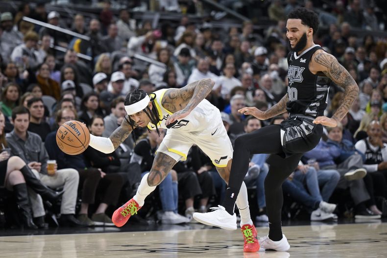 Jordan Clarkson, del Jazz de Utah, recibe una zancadilla de Julian Champagnie, de los Spurs de San Antonio, en el partido del martes 26 de diciembre de 2023 (AP Foto/Darren Abate)