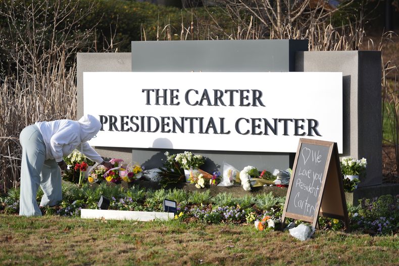 Christine Mason, de Atlanta, coloca flores a la entrada del Centro Presidencial Jimmy Carter el lunes 30 de diciembre de 2024, en Atlanta. El expresidente Carter falleció el domingo en su casa en Plains, Georgia, a la edad de 100 años. (AP Foto/John Bazemore)