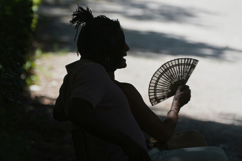 ARCHIVO - Un hombre se abanica mientras descansa en un día de calor en el parque del Retiro, en Madrid, el 28 de junio de 2025. (AP Foto/Paul White, archivo)