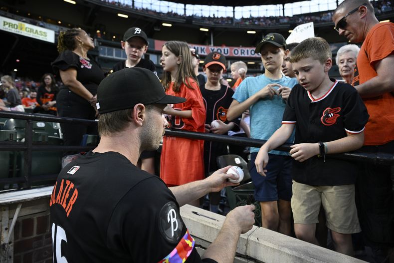 El jardinero de los Orioles Austin Slater (15) firma autógrafos a aficionados previo a un juego ante los Tigres de Detroit, el viernes 20 de septiembre de 2024, en Baltimore. (AP Foto/Nick Wass)