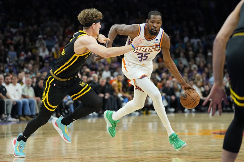 Kevin Durant, alero de los Suns de Phoenix, avanza frente a Brandin Podziemski, de los Warriors de Golden State, el miércoles 22 de noviembre de 2023 (AP Foto/Matt York)