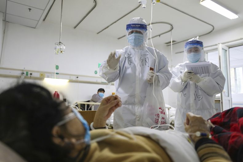 ARCHIVO – Trabajadores sanitarios revisan a pacientes en el hospital Jinyintan, designado para pacientes con COVID-19 en estado crítico, en Wuhan, provincia de Hubei, en el centro de China, el 13 de febrero de 2020. (Chinatopix vía AP, Archivo)