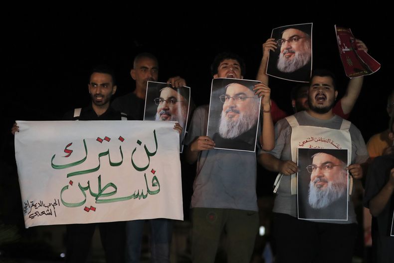 Hombres libaneses y palestinos sostienen retratos del dirigente de Hezbollah, Sayyed Hassan Nasrallah, y una pancarta en árabe en la que se lee: No se quedarán con Palestina, mientras gritan consignas durante una protesta en la ciudad portuaria meridional de Sidón, Líbano, el sábado 28 de septiembre de 2024. (Foto AP/Mohammed Zaatari)