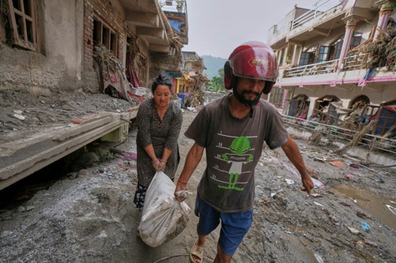 Residentes recuperan sus pertenencias de casas dañadas tras una inundación repentina en la zona de Devighat, en el distrito de Nuwakot, el viernes 28 de agosto de 2026, en Nepal. (AP Foto/Rajesh Kumar Singh)