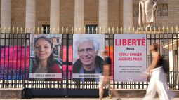 ARCHIVO - La gente pasa junto a los retratos de los franceses Cécile Kohler y Jacques Paris, quienes estuvieron presos en Irán, frente a la Asamblea Nacional Francesa, en París el 3 de julio de 2025. (Foto AP/Aurelien Morissard, Archivo)