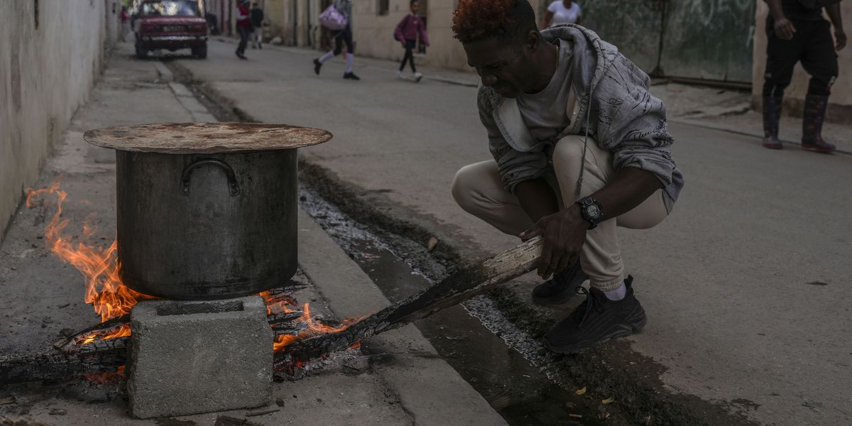 Un hombre cocina sopa sobre una fogata en una acera durante un apagón en La Habana, Cuba, el miércoles 4 de diciembre de 2024. (AP Foto/Ramón Espinosa)