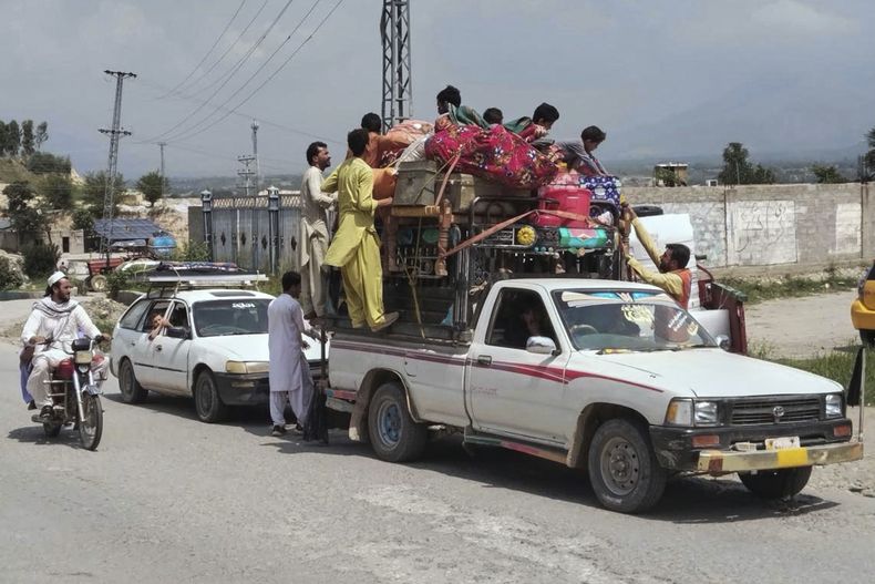 Voluntarios ofrecen agua a personas que huyeron de sus hogares en otras zonas del país debido a una operación de las fuerzas de seguridad contra insurgentes, en una carretera cerca de Khar, la principal localidad de Bajaur, un distrito del noroeste de Pakistán en la frontera con Afganistan, el 11 de agosto de 2025. (AP Foto/Anwarullah Khan)