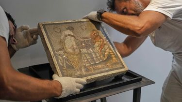 Restauradores exhiben un mosaico romano que representa a una pareja de amantes, que fue repatriado desde Alemania, en el parque arqueológico de Pompeya, Italia, el martes 15 de julio de 2025. (Foto AP/Gregorio Borgia)
