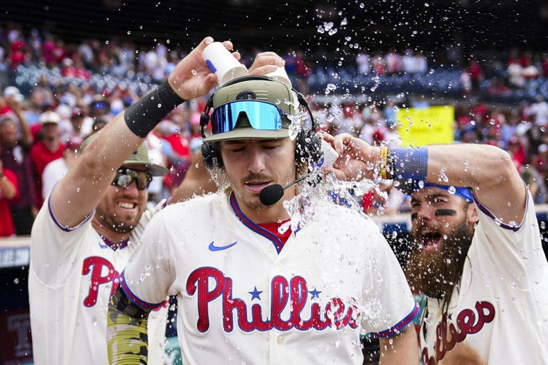 Kody Clemens y Brandon Marsh de los Filis lanza agua sobre Bryson Stott tras el triunfo después de que Stott conectó un jonrón en la séptima entrada en el juego ante los Cachorros de Chicago el domingo 21 de mayo del 2023. (AP Foto/Matt Rourke)