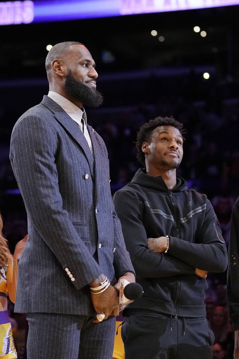 ARCHIVO - LeBron James (izquierda) y su hijo Bronny escuchan una ceremonia donde se honra al primero como líder anotador en la historia de la NBA, el 9 de febrero de 2023 (AP Foto/Mark J. Terrill)