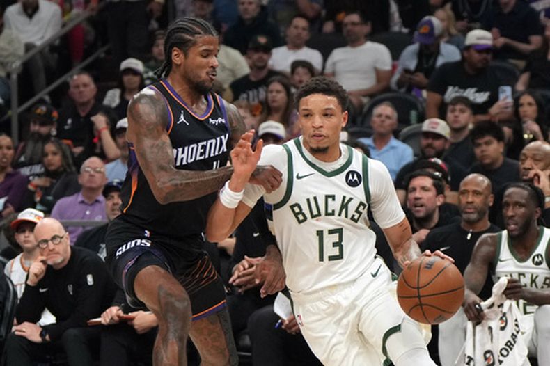El base de los Bucks de Milwaukee, Ryan Rollins (13), penetra ante la defensa del base de los Suns de Phoenix, Jalen Green, durante la primera mitad de un juego de baloncesto de la NBA, el sábado 21 de marzo de 2026, en Phoenix. (Foto AP/Rick Scuteri)