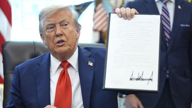 El presidente Donald Trump sostiene una orden ejecutiva firmada que requiere que el Departamento de Justicia investigue los casos de quema de banderas, en la Oficina Oval de la Casa Blanca, el lunes 25 de agosto de 2025, en Washington. (AP Foto/Evan Vucci)