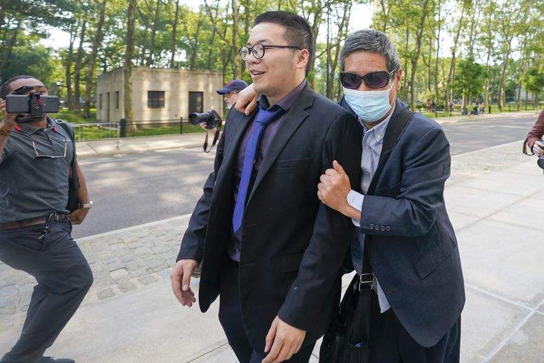 Zhu Yong (derecha) trata de evadir a los fotógrafos al salir de la corte federal de Brooklyn, el miércoles 31 de mayo de 2023, en Nueva York. (AP Foto/Mary Altaffer)