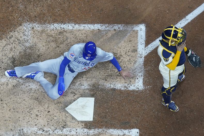 El puertorriqueño Luis Vázquez anota por los Cachorros de Chicago frente al venezolano William Contreras, de los Cerveceros de Milwaukee, en el décimo inning del juego del martes 28 de mayo de 2024 (AP Foto/Morry Gash)