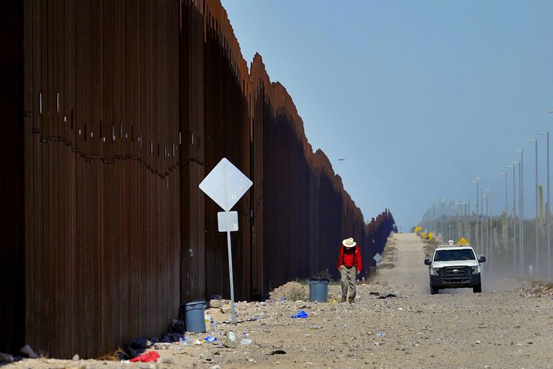 El profesor de escuela retirado Tom Wingo, del grupo Samaritanos Sin Frontera, camina lo largo del muro fronterizo al tiempo que un agente de la Patrulla Fronteriza de Estados Unidos patrulla el área, el martes 29 de agosto de 2023, cerca de Lukeville, Arizona. (AP Foto/Matt York)