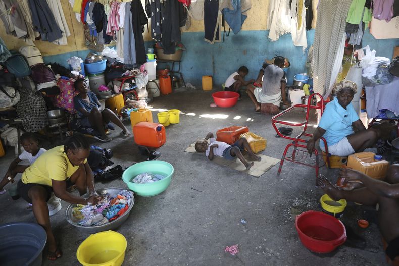 Familias desplazadas por la violencia de las pandillas lavan ropa dentro de una escuela en la que se han estado resguardando durante más de un año, el viernes 20 de septiembre de 2024, en Puerto Príncipe, Haití. (AP Foto/Odelyn Joseph)