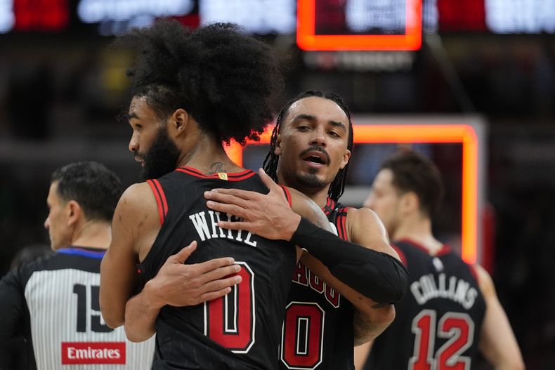 El escolta de los Bulls de Chicago Tre Jones (30), a la derecha, y el escolta Coby White (0) celebran la victoria de su equipo sobre los Nets de Brooklyn en un partido de baloncesto de la NBA el jueves 13 de marzo de 2025, en Chicago. (AP Foto/Erin Hooley)