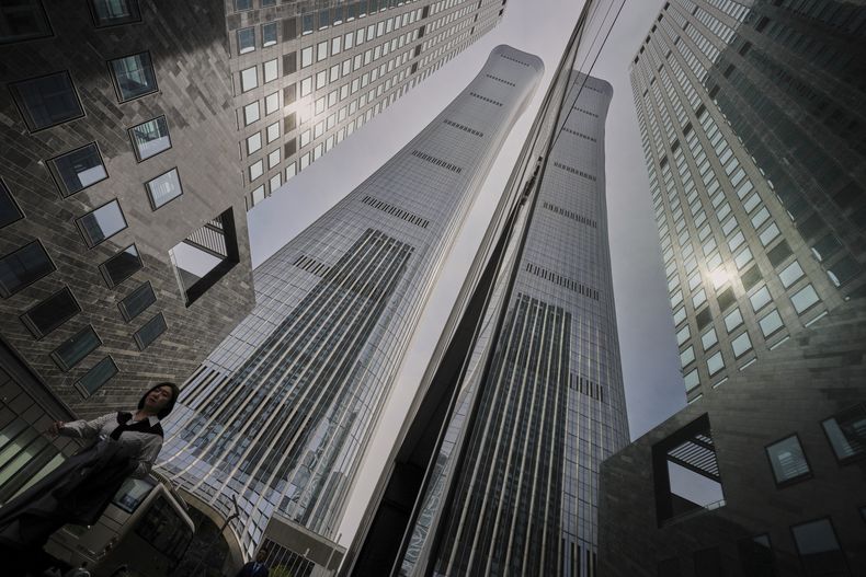 Una mujer camina junto a un rascacielos con oficinas en el distrito de negocios de Beijing, el 8 de abril de 2025. (AP Foto/Andy Wong)