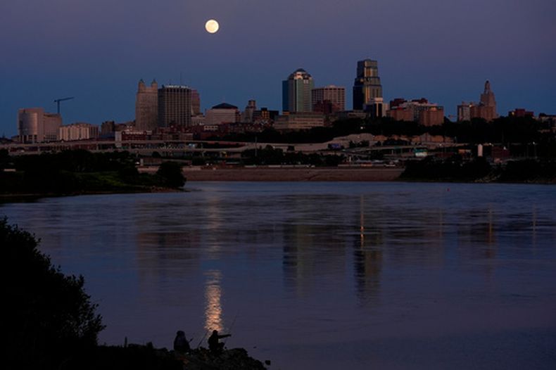 ARCHIVO - Un par de personas pescan en el río Kansas con la luna llena sobre la ciudad de Kansas City, el 11 de mayo de 2025. (AP Foto/Charlie Riedel)