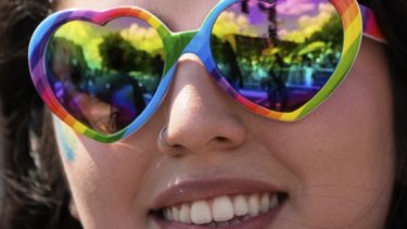 Una persona con gafas en forma de corazón y con los colores del arcoíris mira el desfile del Orgullo Mundial LGBTQ+ el sábado 7 de junio de 2025, en Washington. (AP Foto/Alex Brandon)