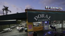 Ciudadanos estadounidenses que inmigraron de Venezuela hace entre 16 y 30 años juegan al dominó fuera de El Arepazo, un restaurante que es un punto de encuentro de la comunidad venezolana en Estados Unidos, en Doral, Florida, el miércoles 2 de abril de 2025. Muchos de los amigos, como César Mena, a la derecha, votaron por el presidente Donald Trump y le siguen apoyando. Mena dijo que tenía familiares y amigos amparados por el TPS, y lo lamentaba por ellos, pero era una situación temporal y había un problema que resolver. (AP Foto/Rebecca Blackwell)
