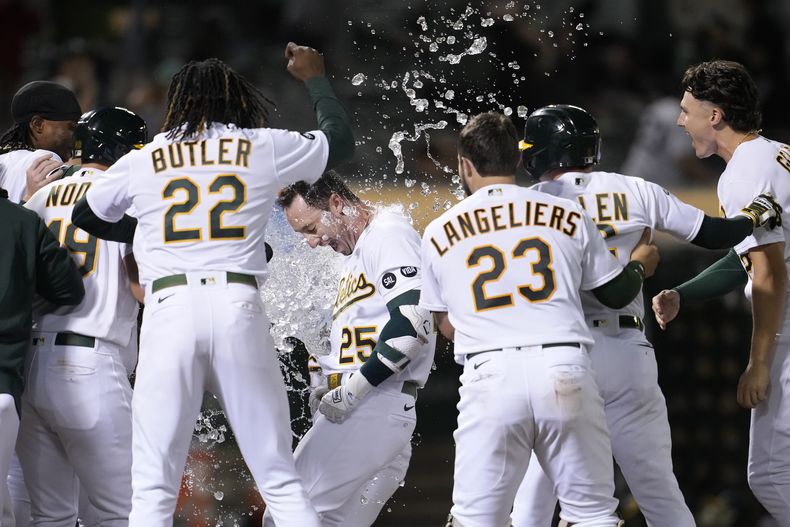 Brent Rooker de los Atléticos de Oakland es felicitado por sus compañeros tras pegar un jonrón de dos carreras en la novena entrada para vencer a los Reales de Kansas City el lunes 21 de agosto del 2023. (AP Foto/Jeff Chiu)