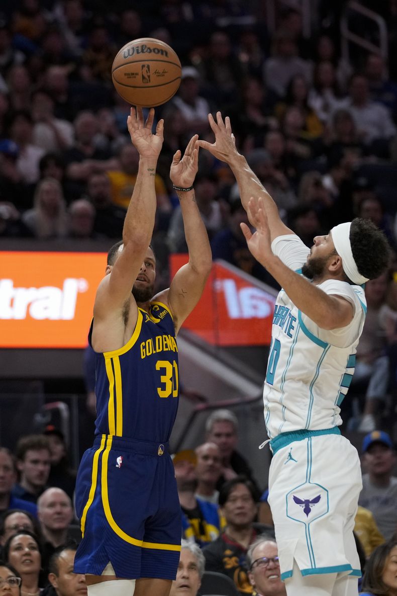 Stephen Curry, de los Warriors de Golden State, dispara frente a su hermano Seth, de los Hornets de Charlotte, el viernes 23 de febrero de 2024 (AP Foto/Godofredo A. Vásquez)