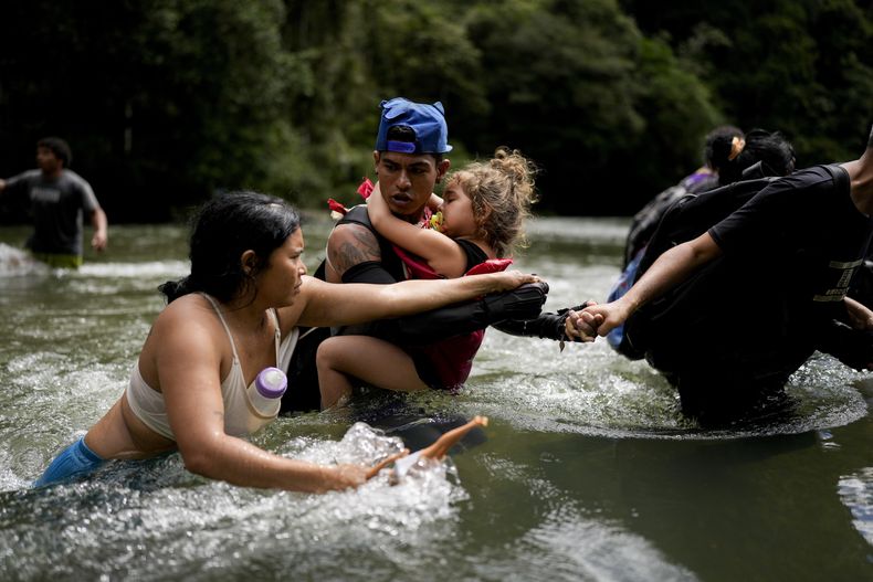 El migrante venezolano Álvaro Calderini lleva a su sobrina a través de un río cerca de Bajo Chiquito, Panamá, después de cruzar el Tapón del Darién desde Colombia en su camino hacia Norteamérica, el sábado 9 de noviembre de 2024. (Foto AP/Matías Delacroix)