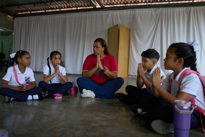 La maestra Jorli Correa dirige una oración con los pocos alumnos que pudieron regresar para el primer día de clases en la escuela UEP Simón Bolívar Fe y Alegría, tras el terremoto, en La Guaira, Venezuela, el martes 15 de septiembre de 2026. (Foto AP/Ariana Cubillos)
