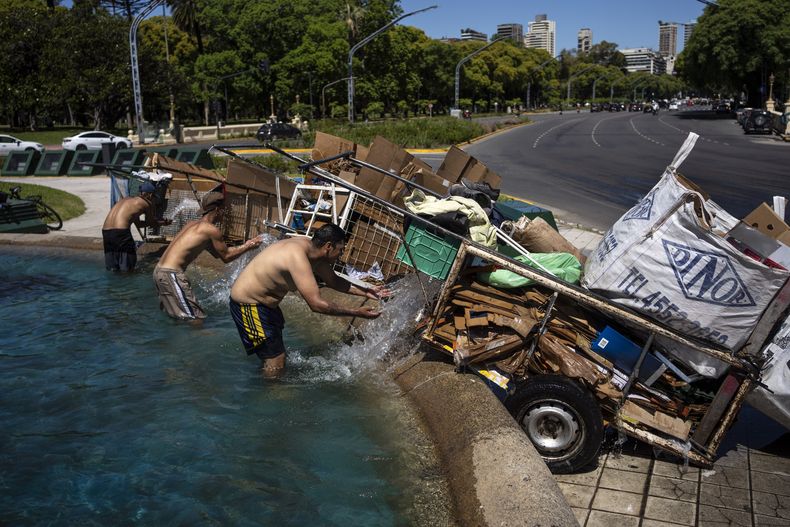 Cartoneros mojan con agua el cartón reciclado recolectado antes de pesarlo en un centro de reciclado, mientras se refrescan en una fuente en Buenos Aires, Argentina, el 11 de diciembre de 2023. La segunda mayor economía de Sudamérica sufre una inflación anual del 143% y cuatro de cada 10 argentinos han caído bajo el umbral de la pobreza. (AP Foto/Rodrigo Abd)