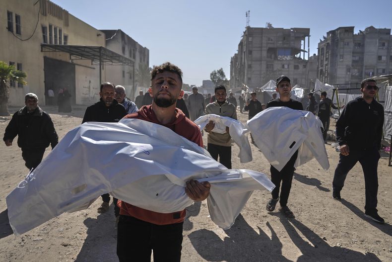 Varias personas cargan con mortajas blancas que cubren los cadáveres de los miembros de la familia Abu Al-Rous, que murieron a causa de un ataque israelí sobre la tienda de campaña en la que vivían, en su funeral en Jan Yunis, en el sur de Gaza, el 17 de abril de 2025. (AP Foto/Abdel Kareem Hana)