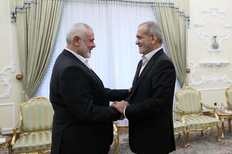 En esta imagen publicada por la oficina de presidencia iraní, el presidente de Irán, Masoud Pezeshkian, a la derecha, estrecha la mano del jefe de Hamás, Ismail Haniyeh, el inicio de su reunión en la oficina del presidente en Teherán, Irán, el martes 30 de julio de 2024. (Oficina de presidencia iraní via AP)