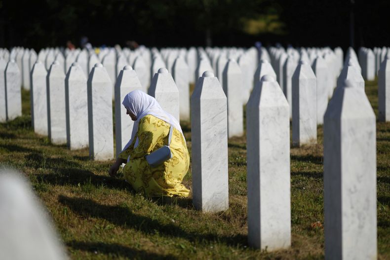 Una mujer llora junto a la tumba de un familiar, víctima del genocidio de Srebrenica, en el Cementerio y Monumento de Potocari, Bosnia, el viernes 11 de julio de 2025. (AP Foto/Darko Bandic)
