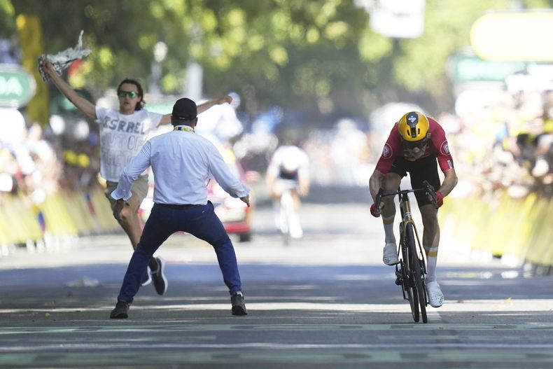 Jonas Abrahamsen rumbo a la meta para ganar la 11ma etapa del Tour de Francia mientras un manifestante, el miércoles 16 de julio de 2025. (AP Foto/Thibault Camus)