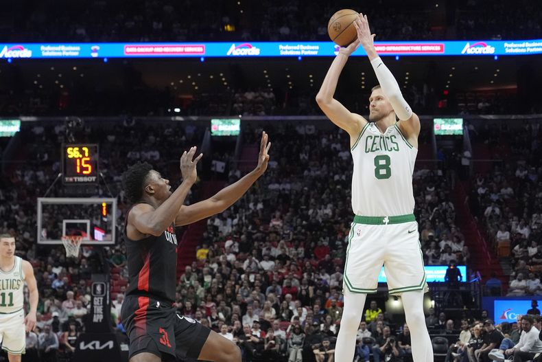 El pívot de los Celtics de Boston, Kristaps Porzingis (8), apunta una canasta de tres puntos sobre el pívot del Heat de Miami, Thomas Bryant (31), durante la primera mitad de un partido de baloncesto de la NBA, el jueves 25 de enero de 2024, en Miami. (AP Foto/Marta Lavandier)