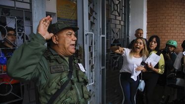 Un oficial de la Guardia Nacional se dirige a los votantes que hacen fila en la Escuela Andrés Bello mientras los observadores electorales de la oposición argumentan que no se les permite ingresar al centro de votación durante las elecciones presidenciales en Caracas, Venezuela, el domingo 28 de julio de 2024. (AP Foto/Cristian Hernández)