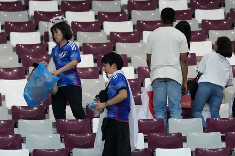 ARCHIVO - Hinchas japoneses limpian las gradas al final del partido entre Alemania y Japón por la Copa Mundial, el 23 de noviembre de 2022, en Doha, Qatar. (AP Foto/Eugene Hoshiko)