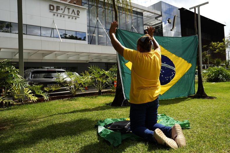 Un partidario del expresidente Jair Bolsonaro reza frente al hospital DF Star, donde se sometió a una cirugía abdominal en Brasilia, Brasil, el lunes 14 de abril de 2025. (AP Foto/Eraldo Peres)