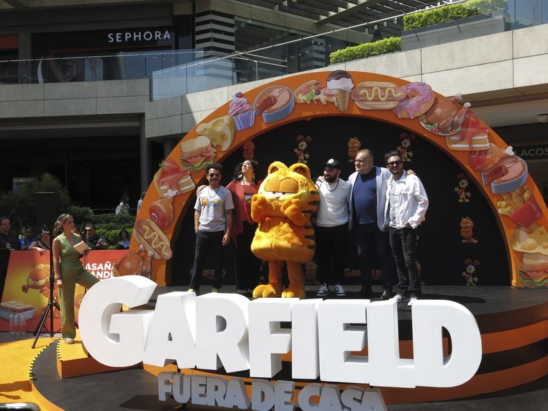 Un artista disfrazado como el personaje Garfield, centro, con los actores de doblaje Guillermo Memo Villegas, de izquierda a derecha, Regina Orozco, Jose Luis Slobotzky, Joaquín Cosio y Ricardo Pérez, posan en la alfombra naranja de la versión en español para Latinoamérica de The Garfield Movie en la Ciudad de México el domingo 28 de abril de 2024. (Foto AP/Berenice Bautista)