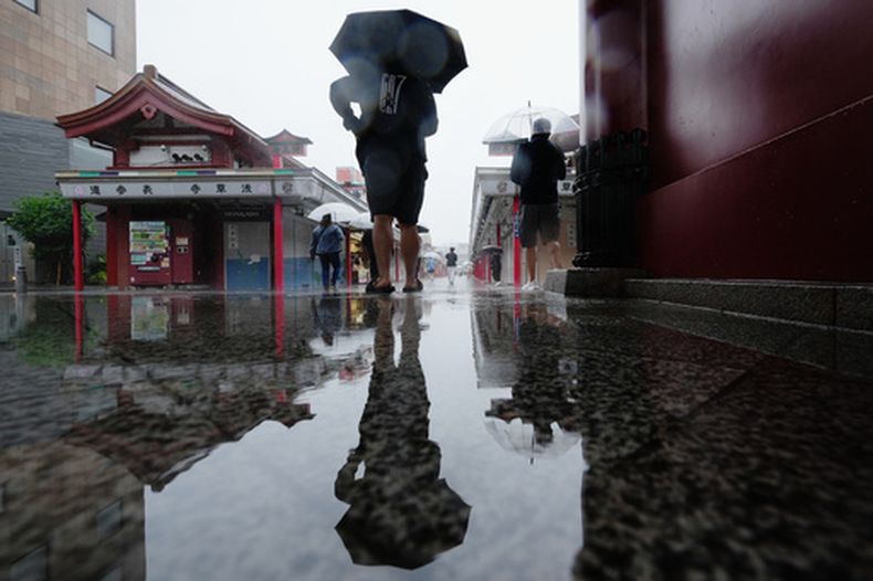 Un hombre se detiene para resguardarse de la lluvia en Tokio, el miércoles 3 de junio de 2026. (AP Foto/Hiro Komae)