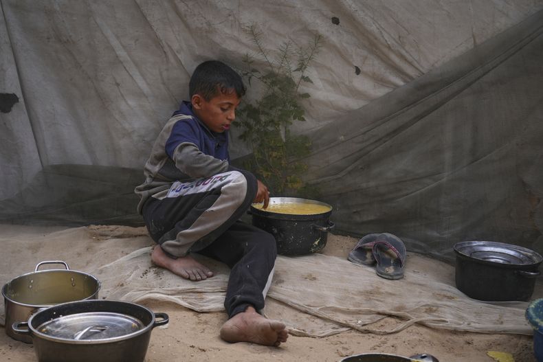 Mohammad Abu Zeid, de 12 años, prueba la comida preparada para su familia en la carpa donde viven en Muwasi, a las afueras de Jan Yunis, en el sur de la Franja de Gaza, el jueves 24 de abril de 2025. (AP Foto/Abdel Kareem Hana)