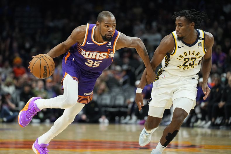 El alero Kevin Durant (35), de los Suns de Phoenix, conduce con el balón mientras defiende Aaron Nesmith (23), de los Pacers de Indiana, durante la segunda mitad del juego de baloncesto de la NBA, el domingo 21 de enero de 2024, en Phoenix. (AP Foto/Matt York)
