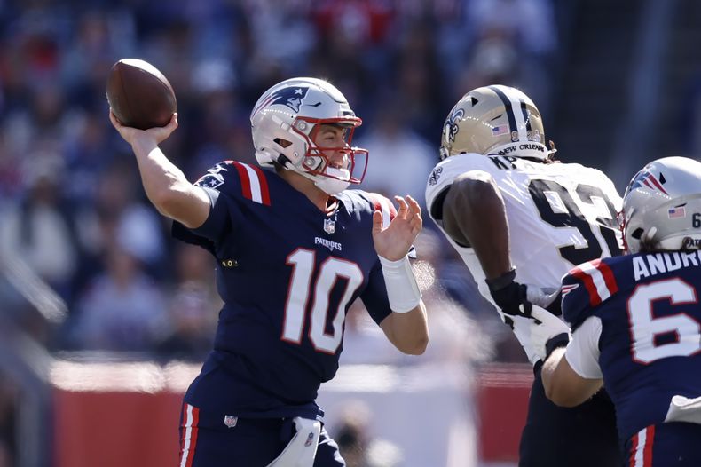 El quarterback de los Patriots de Nueva Inglaterra Mac Jones pasa el balón bajo presión del defensive end de los Saints de Nueva Orleans Tanoh Kpassagnon durante el encuentro del domingo 8 de octubre del 2023. (AP Foto/Michael Dwyer)