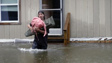 Un hombre carga objetos personales por una zona inundada desde una casa en Bridgewater, Vermont, el lunes 10 de julio de 2023. Las fuertes lluvias anegaron zonas del nordeste de Estados Unidos, donde destruyeron carreteras, forzaron evacuaciones y paralizaron parte del tráfico aéreo. (AP Foto/Hasan Jamali)